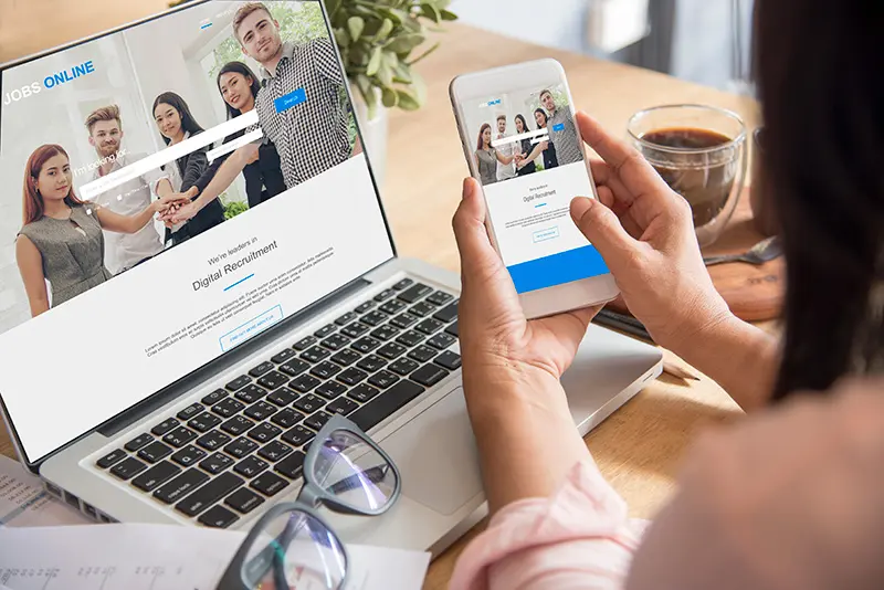 Small business owner reviewing a mobile-friendly website design with responsive layouts displayed on a smartphone, tablet, and laptop.